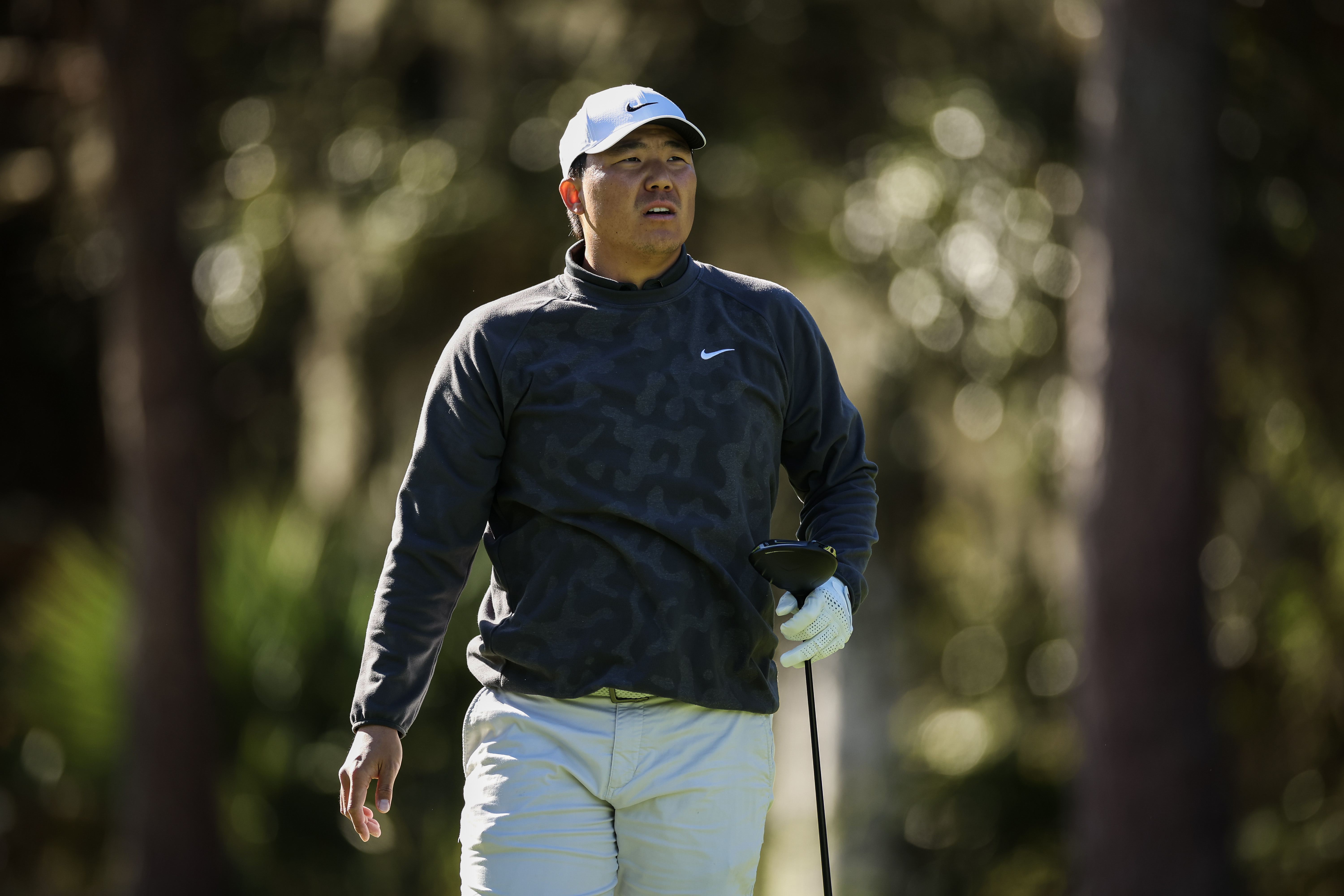 Norman Xiong watches a tee shot with a driver in hand