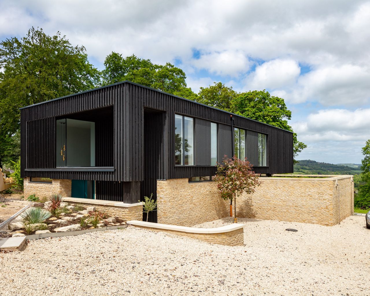 black timber clad house with stone driveway