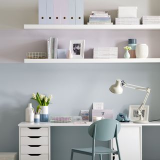 White desk and floating shelves in front of pastel wall