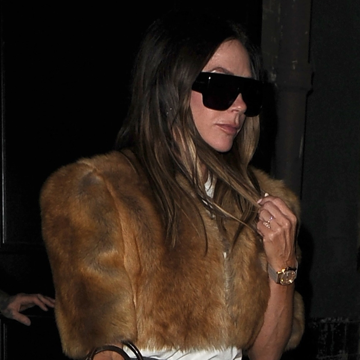 Victoria Beckham wears oversize sunglasses and a cropped fur jacket.