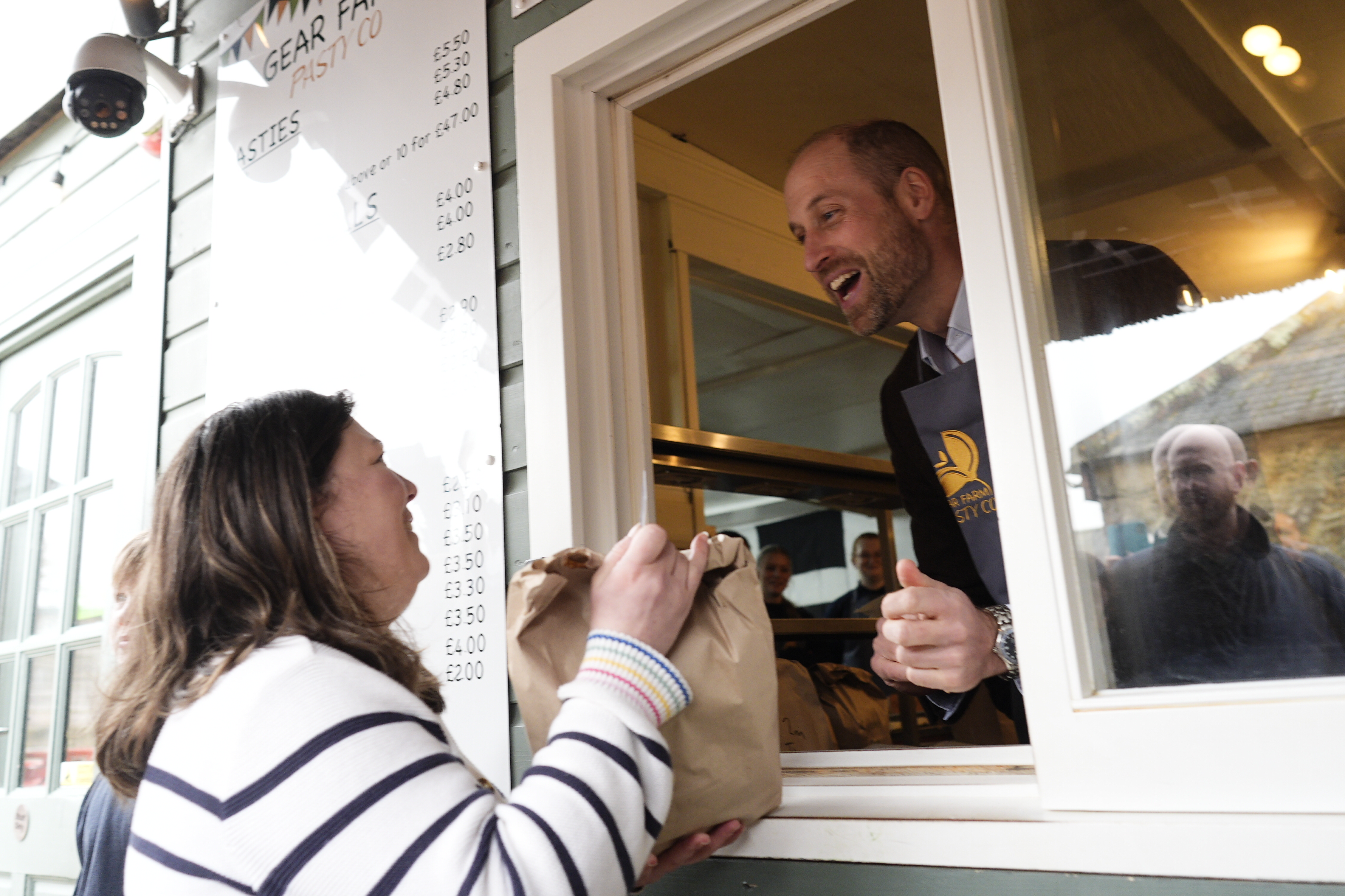 Prince William passing a bag out the window of a pasty shop