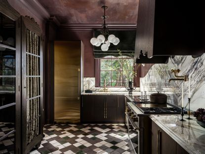 a dark red kitchen with a brass fridge