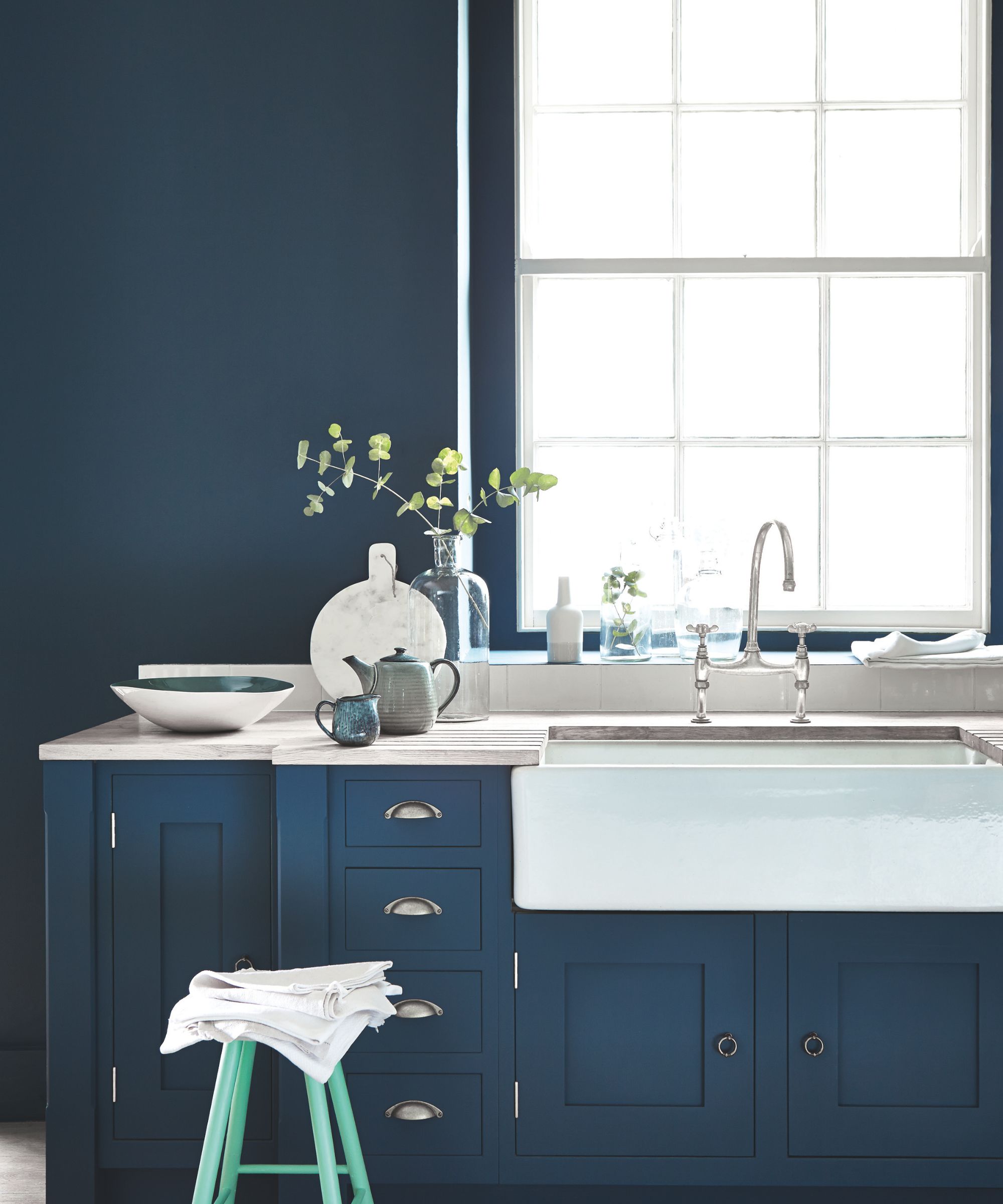 dark blue kitchen cabinets and walls with butler's sink in front of window
