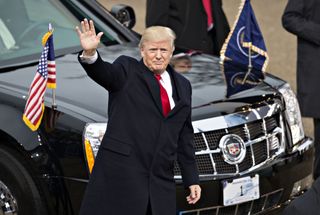 U.S. President Donald Trump waves while walking near the White House during the 58th presidential inauguration parade in Washington, D.C