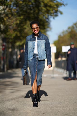 Tamu McPherson wears sunglasses, a bi-color dark blue and pale blue denim jacket, a white t-shirt, a blue slit denim skirt, a bag, black leather ankle boots, outside Stella McCartney, during the Womenswear Spring/Summer 2024 as part of Paris Fashion Week on October 02, 2023 in Paris, France.