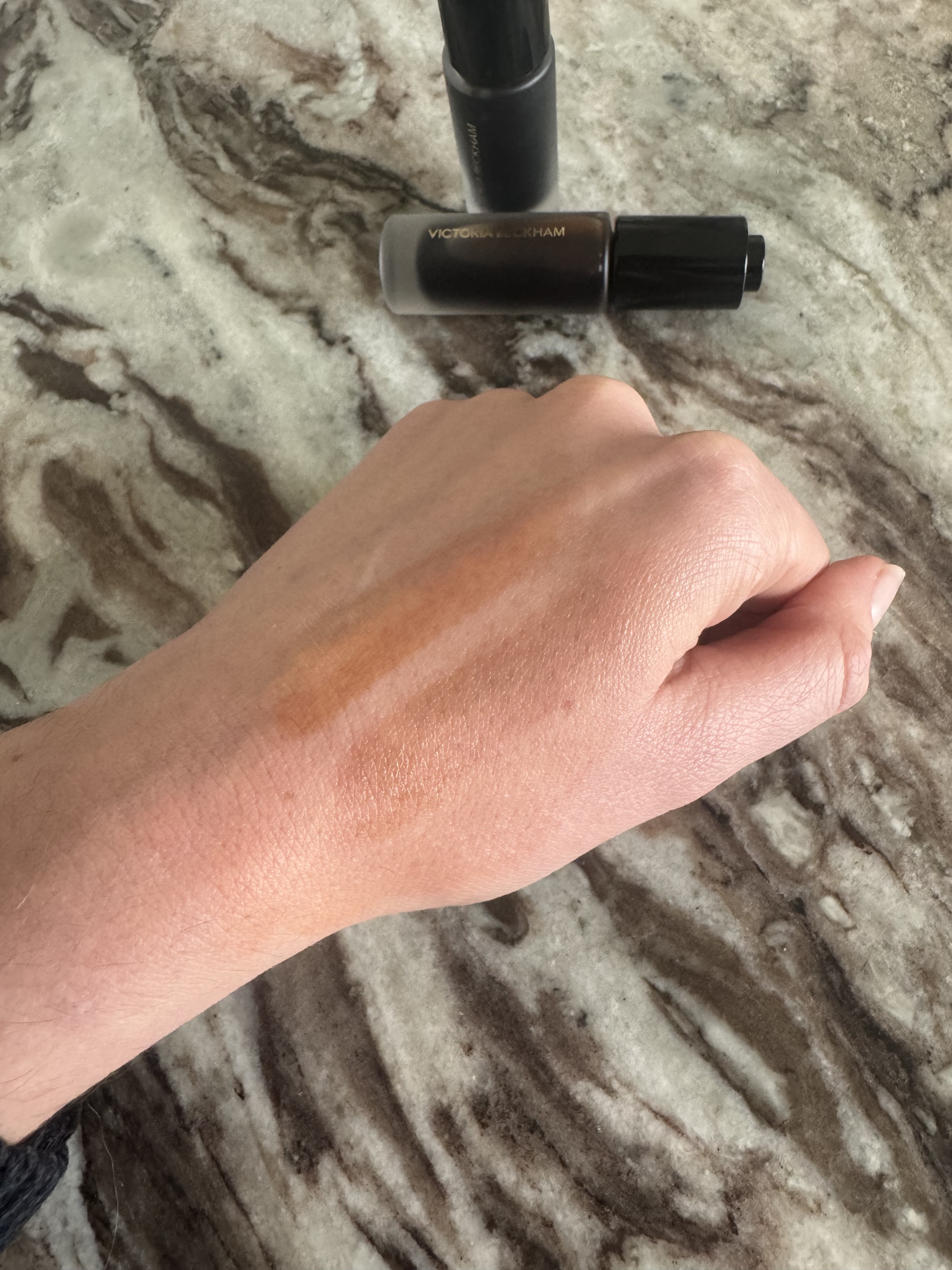 Swatches of the Victoria Beckham Beauty Colour Wash Bronze Tints, in Tanline, a honey, golden bronze, and Heatwave, a deeper bronze hue