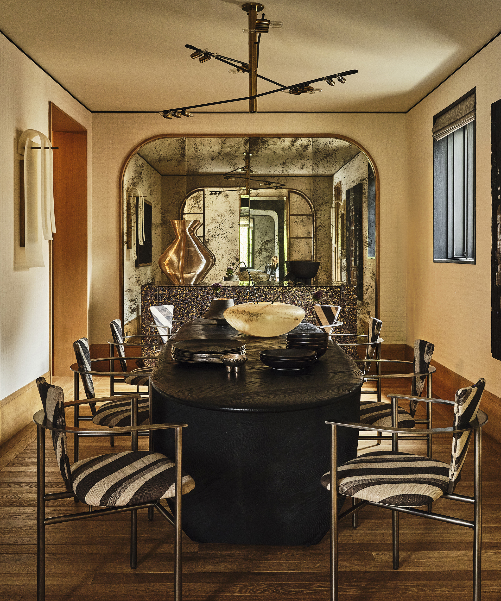 large dining room with black and white striped dining chairs and vintage mirror