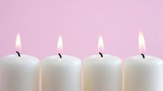 white candles burning on pink background