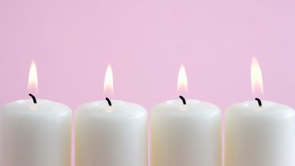 white candles burning on pink background