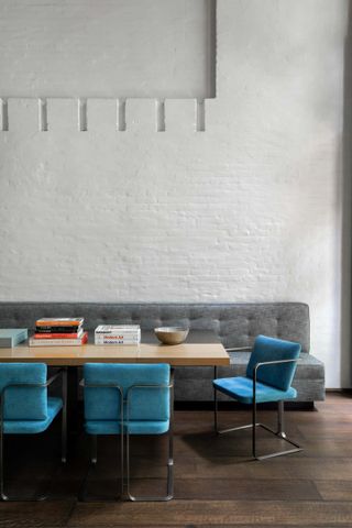 A grey wall and bench with blue chairs