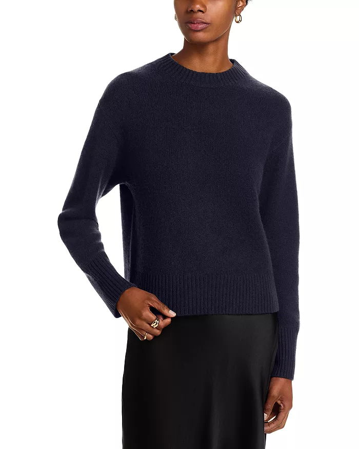A model wearing a navy sweater and black skirt