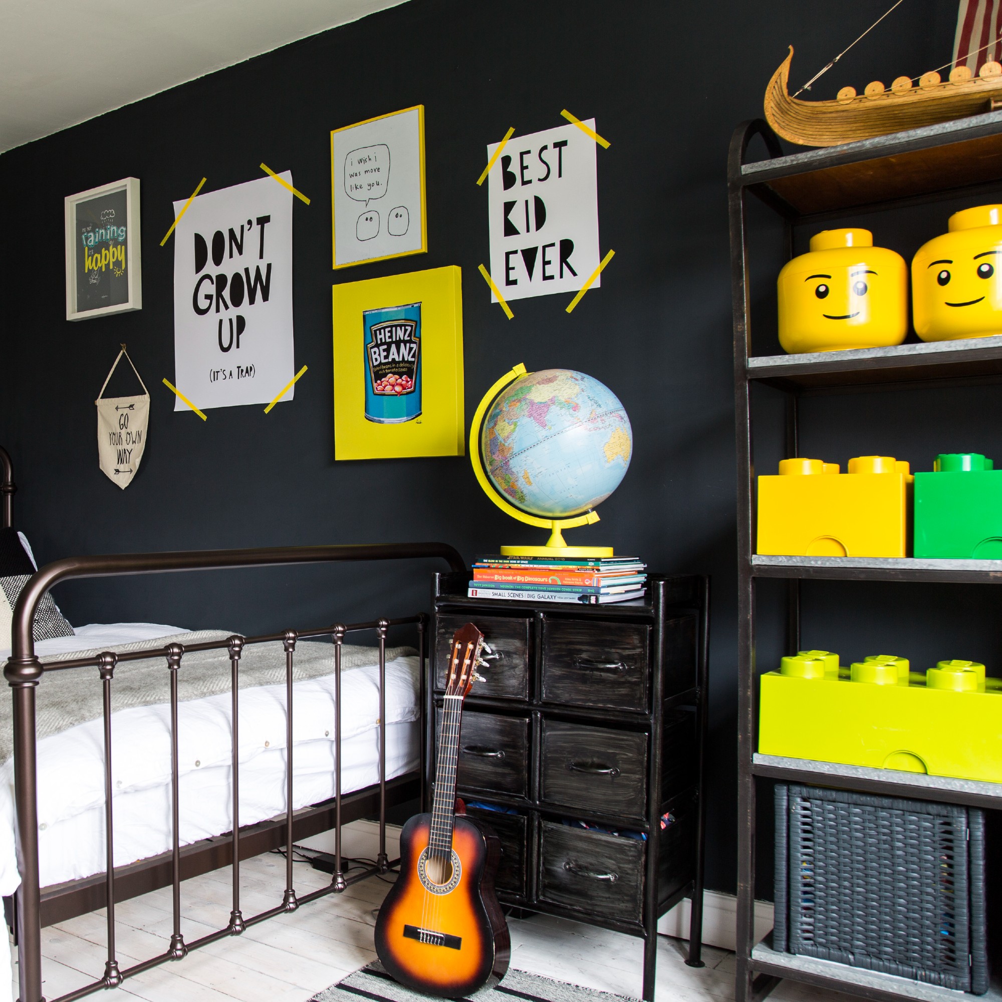 A black-painted teenager's bedroom with a Lego display and a gallery wall above the bed