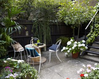 a courtyard gaden with a dining set and pots of container flowers