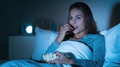 woman eating popcorn in bed