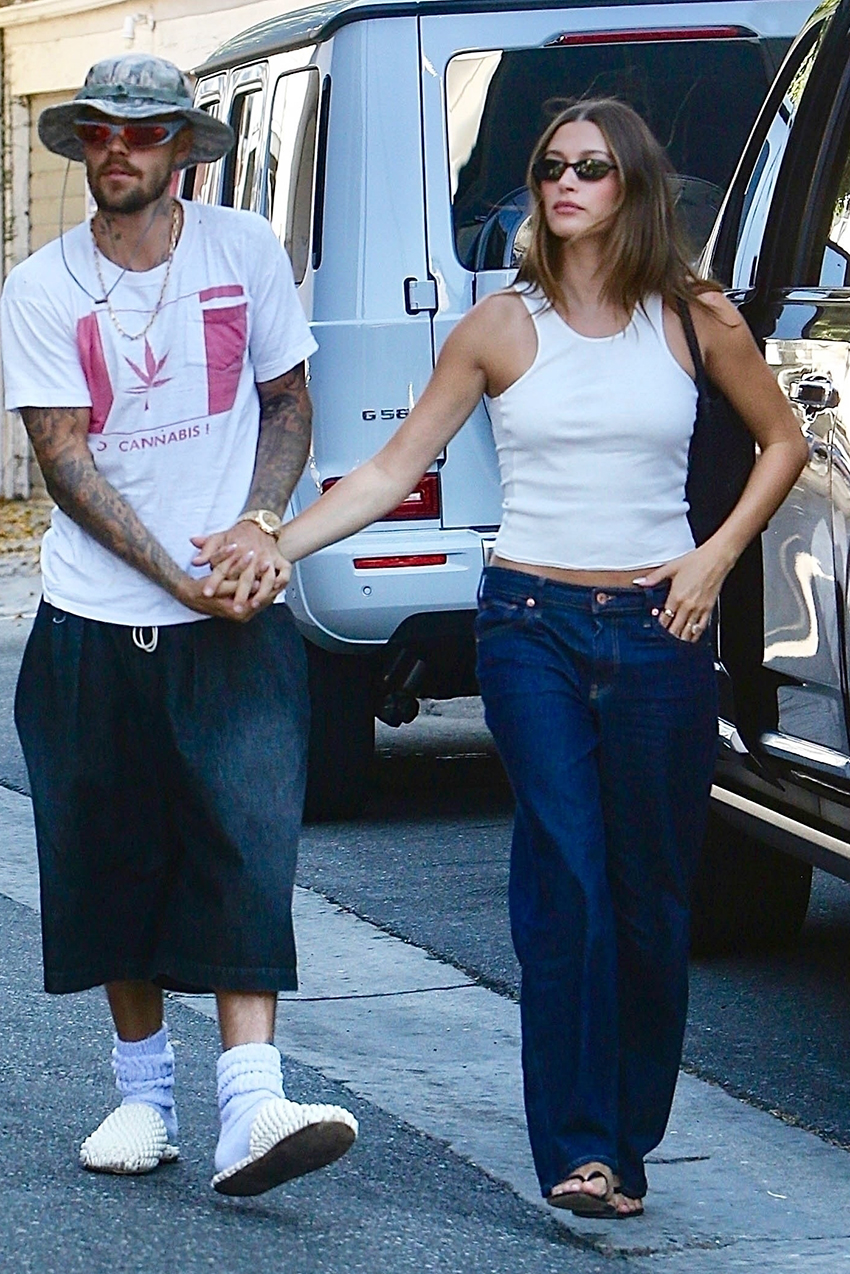 Hailey Bieber wearing a white tank top, dark denim Gap jeans, and The Row flip-flops
