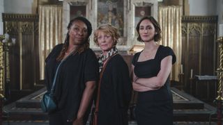 Jo Martin as Suzie, Samantha Bond as Judith and Cara Horgan as Becks all dressed in black stand in a church in The Marlow Murder Club.