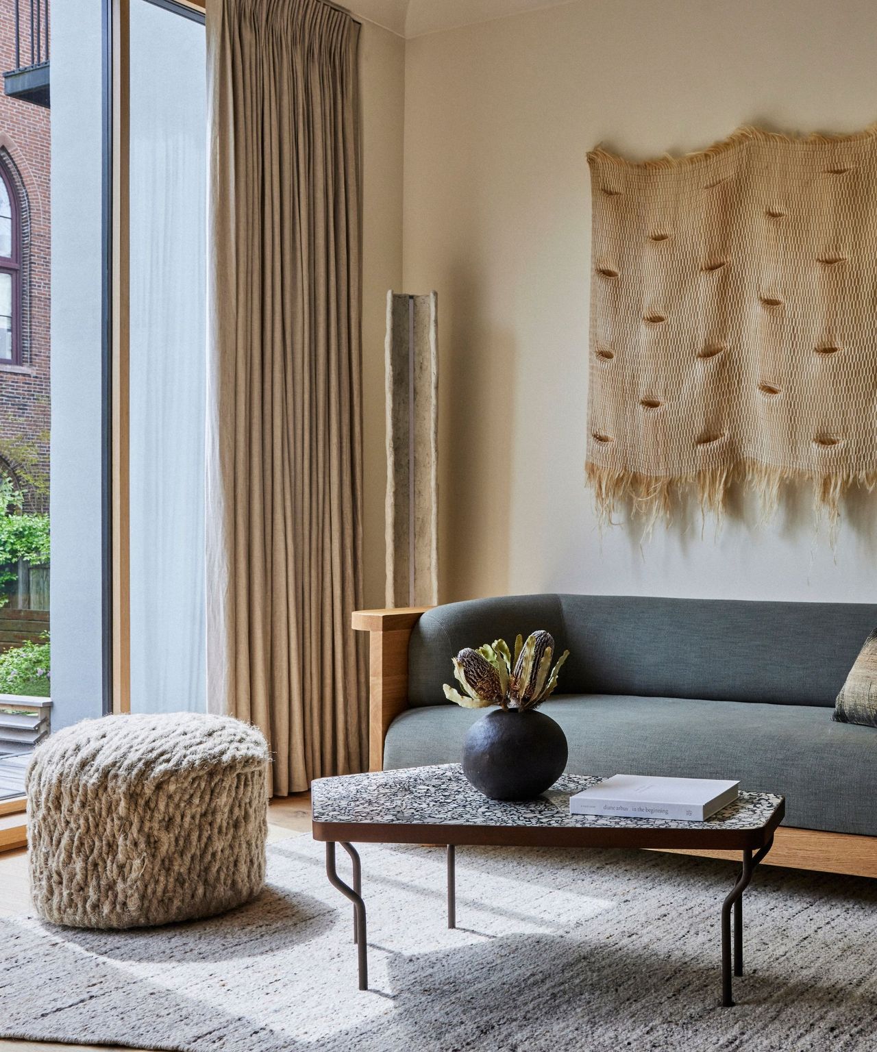 A living room with a gray sofa and floor-to-ceiling windows