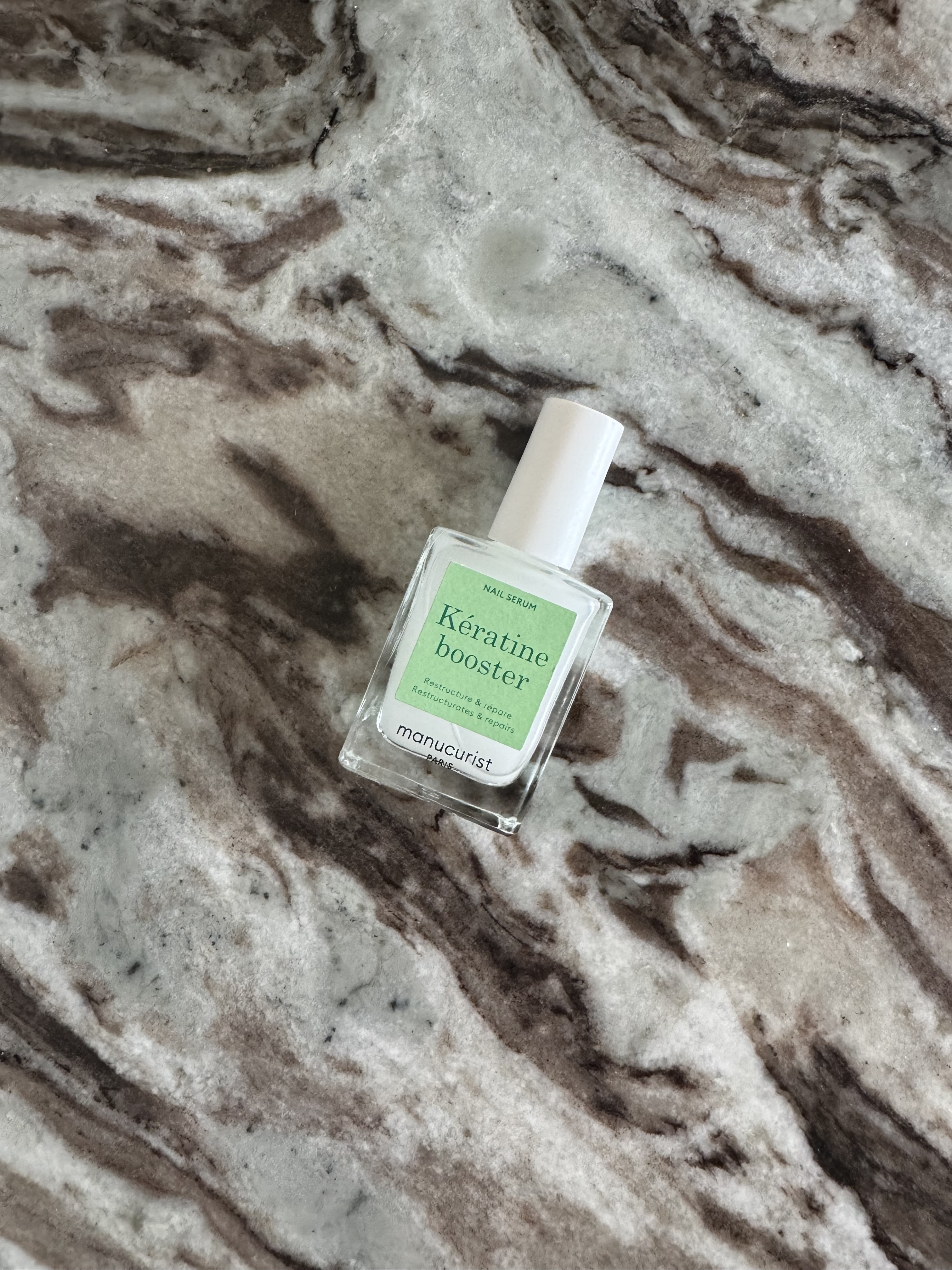 The manucurist keratine booster nail serum on a marble surface