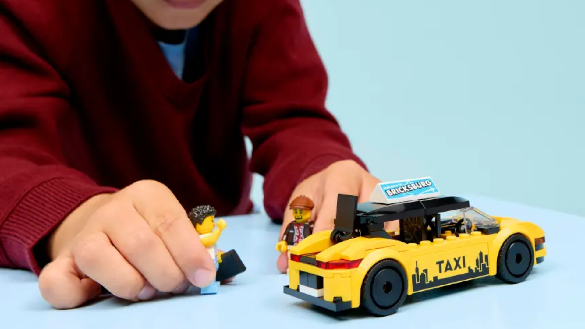 A child plays with the Lego Yellow Taxi set on a blue surface