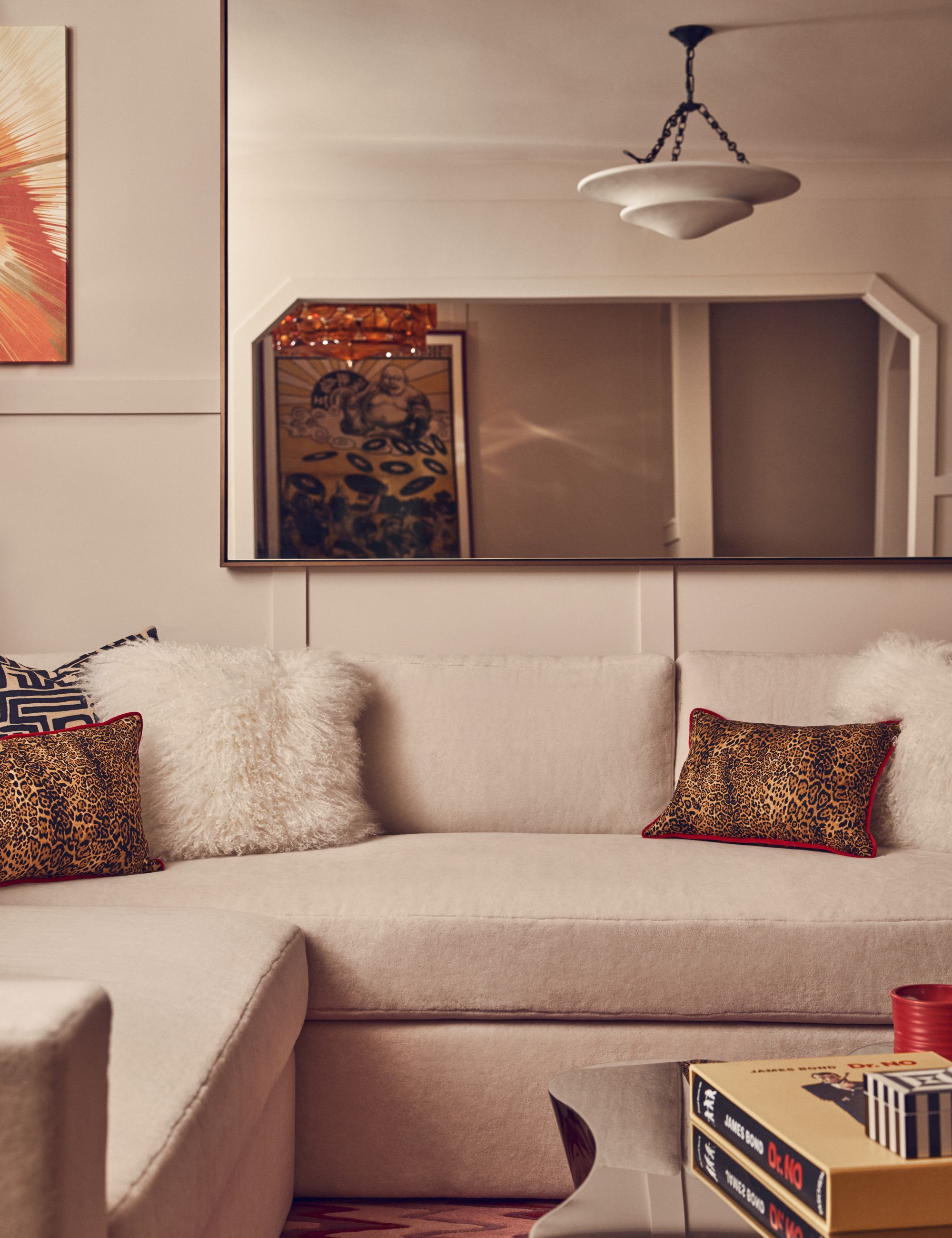 White linen sofa with leopard print cushions, white fluffy cushions and mirrored coffee table and mirror