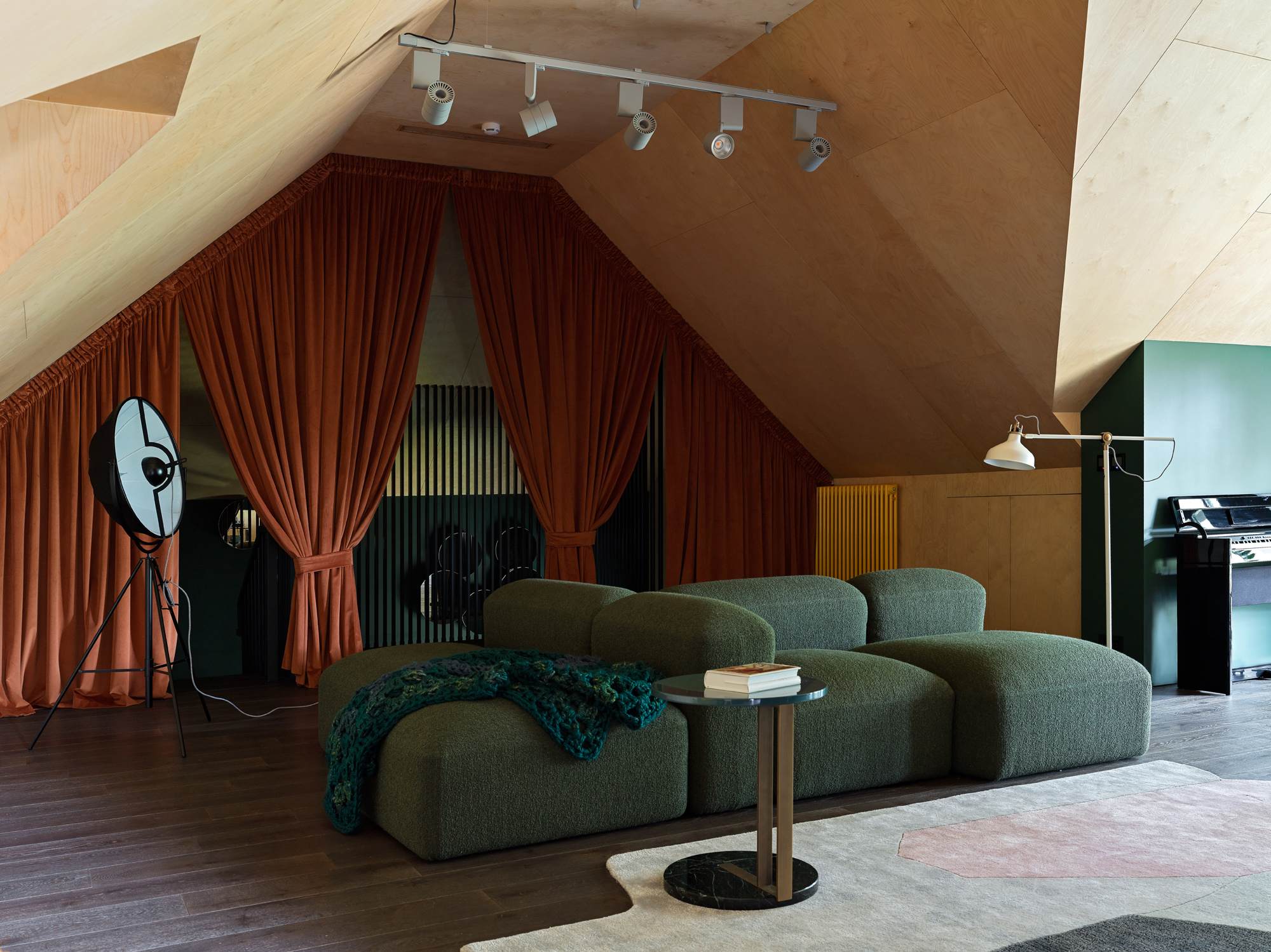 a music room with ply ceilings and a green sofa with orange curtains