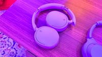 Sony WH-CH730N wireless headphones in lavender on a wooden table 