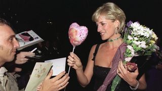 Princess Diana in a black square neck dress taking flowers and balloons from the crowd on her 36th birthday