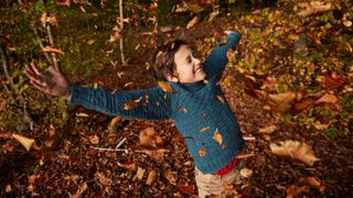 Cheerful boy enjoying amidst falling autumn leaves