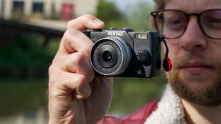 Man holding Pentax Q10 mirrorless camera up to his face