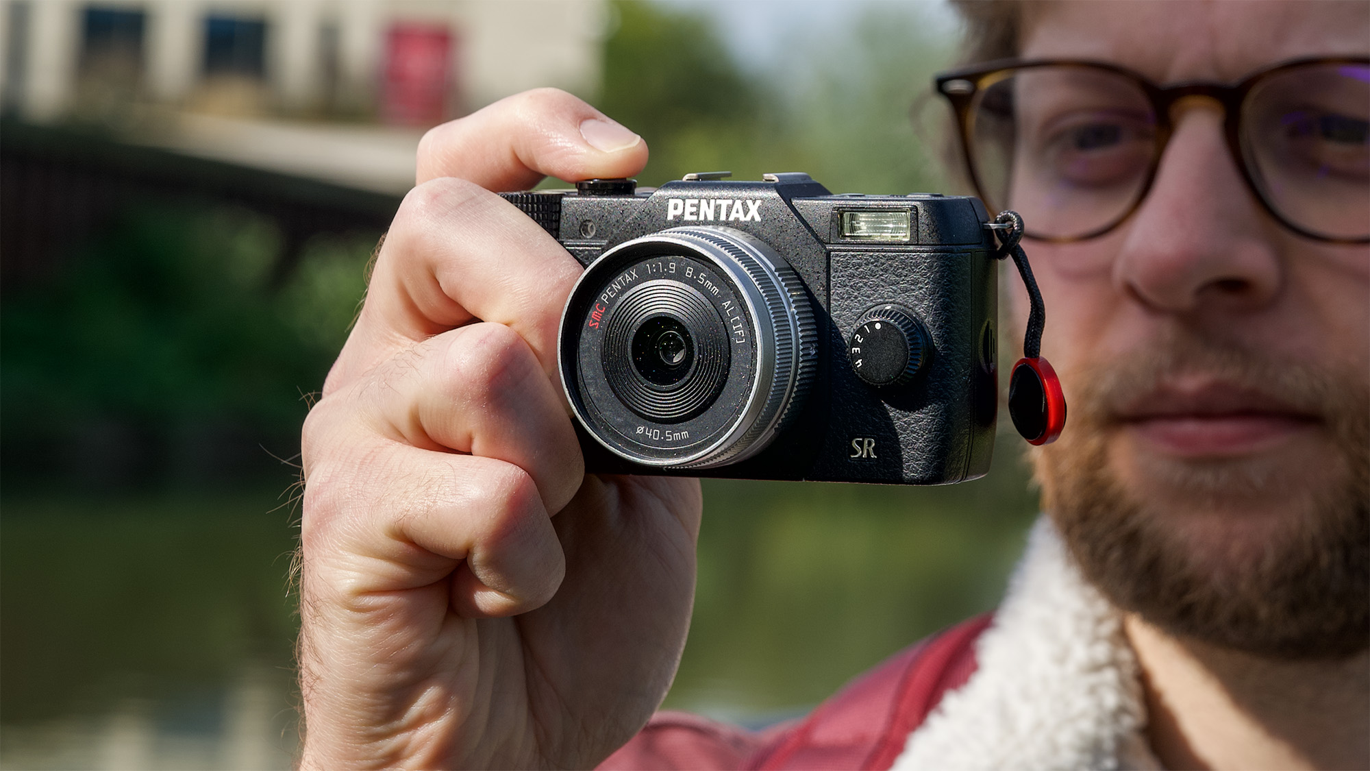 Man holding Pentax Q10 mirrorless camera up to his face