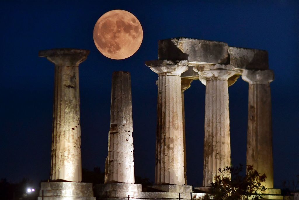 super blue moon above five ancient column structures.