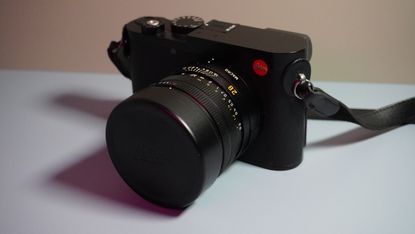 The Leica Q3 camera on a grey and pink background