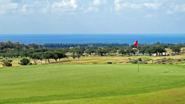 Looking down over the closing green with the course below and the blue sea beyond