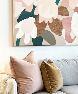 large abstract print with warm pink tones matching the pillows on the couch