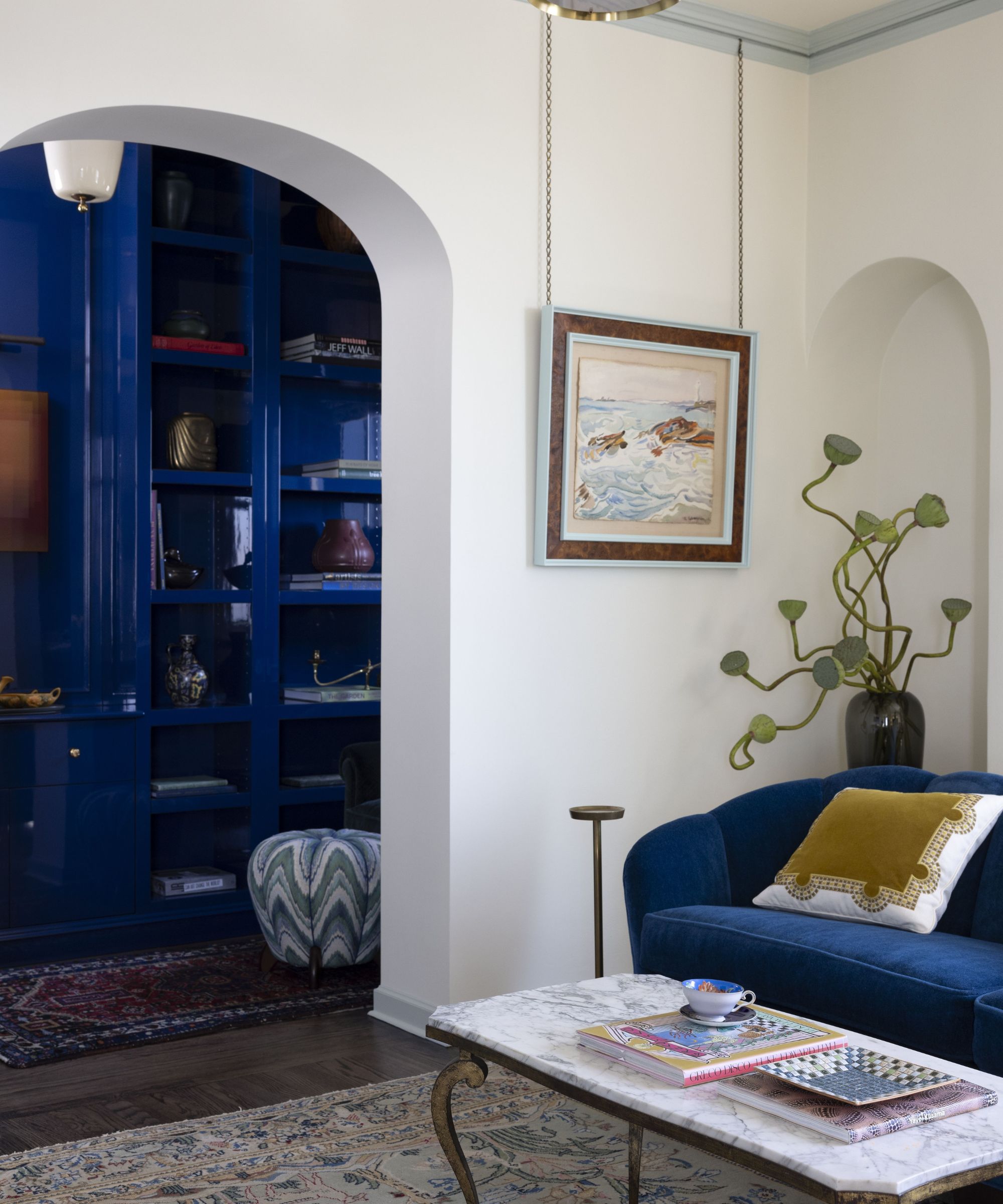 Corner of a white living room with arch into a blue glossy painted home office