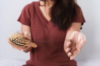 Woman holding a dirty hairbrush that needs to be cleaned