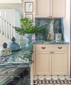 kitchen with green marble top and chequered tiled floor and light pink cabinetry