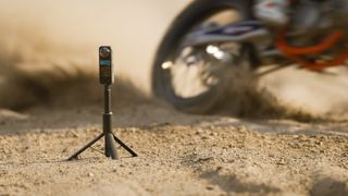 Insta360 X4 standing in front of a Supercross bike on a dusty path