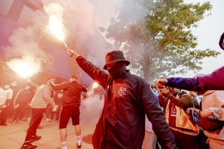 A masked New York City FC fans holds up a pyrotechnic before the Hudson River Derby game: New York City FC vs New York Red Bulls outside Citi Field in Queens, New York