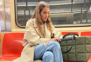 Vee Collective founder Lili Radu wearing a trench coat, jeans, Miu Miu ballet flats, and a Vee Collective Porter Tote in NYC