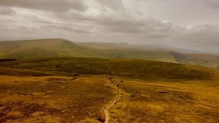 A long view of Bannau Brycheiniog, with a path snaking through the middle of the picture.