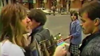 Bruce Dickinson holding an album and talking to someone on the street