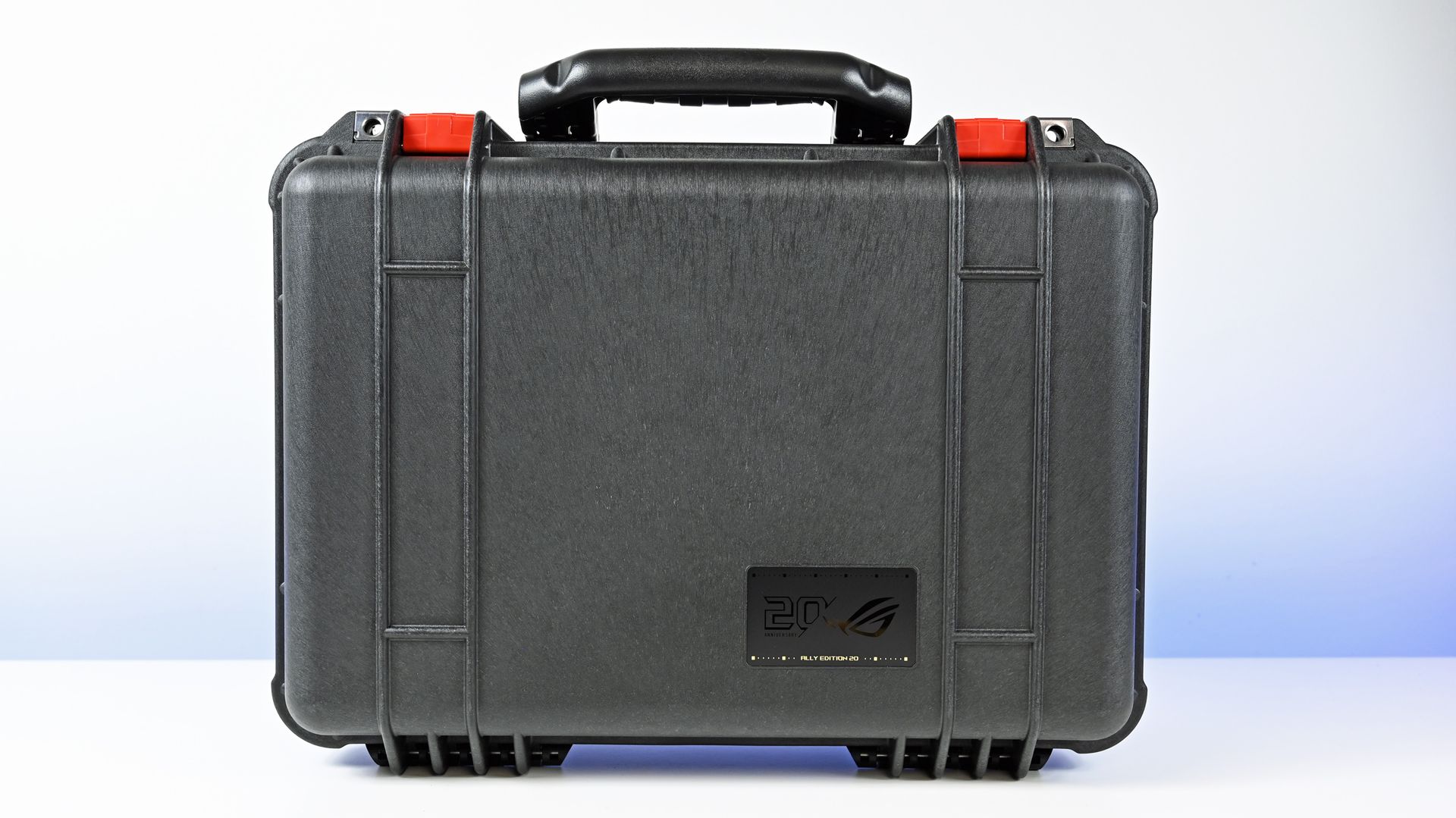 Front view of the closed black Pelican Protector Case with red latches and a gold 20th Anniversary ROG badge.