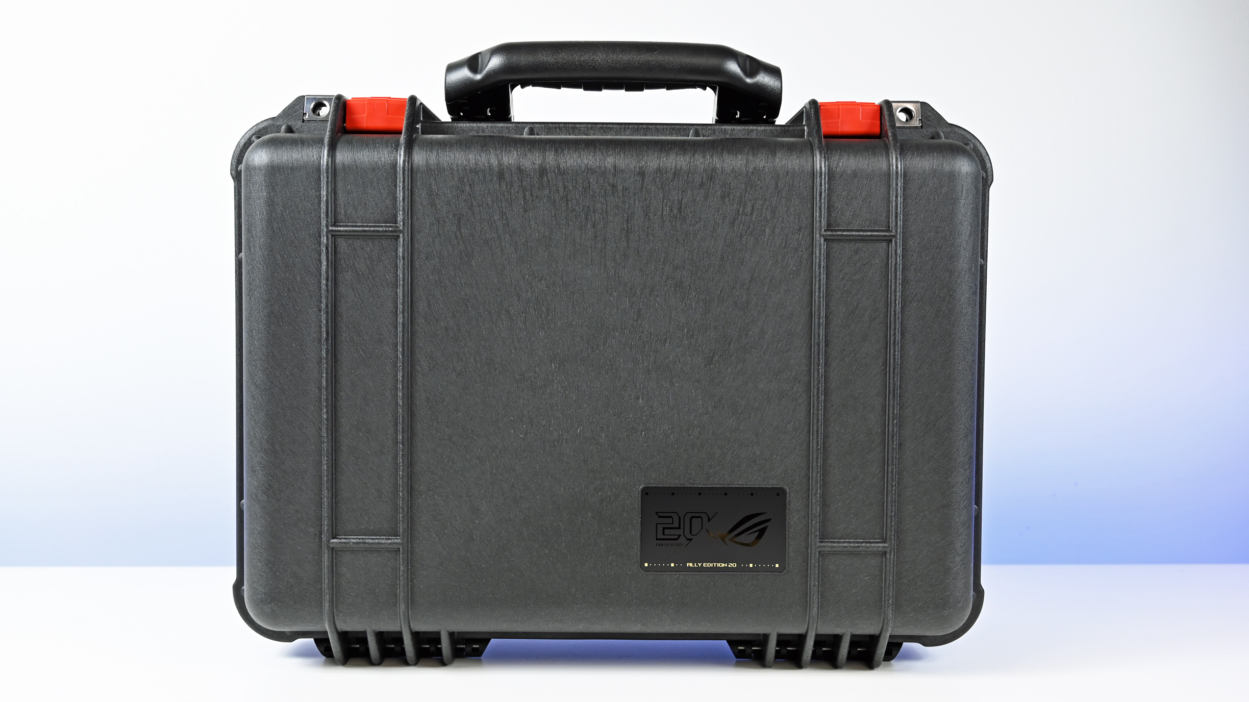 Front view of the closed black Pelican Protector Case with red latches and a gold 20th Anniversary ROG badge.