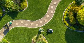 Overhead shot of a person mowing the lawn in different directions to support an essential summer lawn care tip