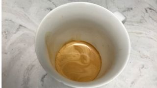De'Longhi Dinamica Plus espresso in a white mug on a countertop