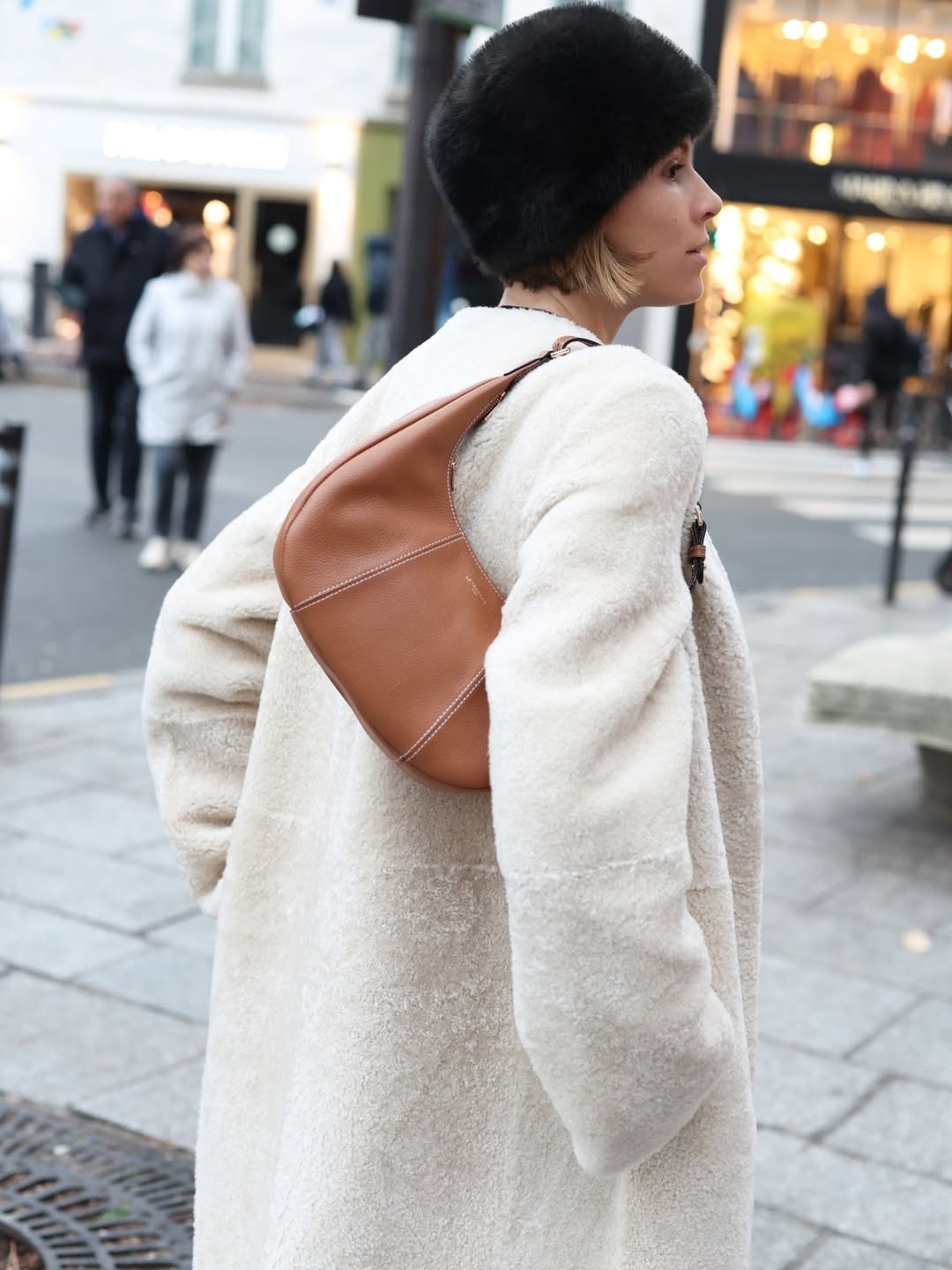 Woman in a white faux-fur coat and a tan bag