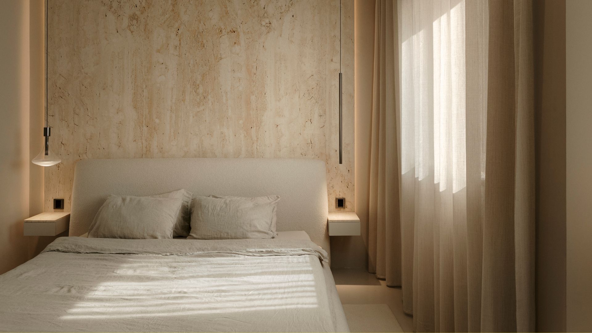A bedroom with semi-sheer window treatments, a stone accent wall, and a bed with a boucle headboard and beige bedding with floating nightstands and pendant lamps on either side