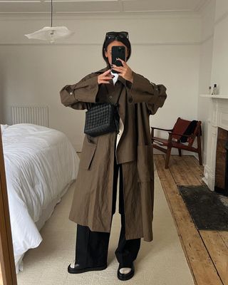 @emswells wears her trench coat with wide-leg trousers and a cross-body bag