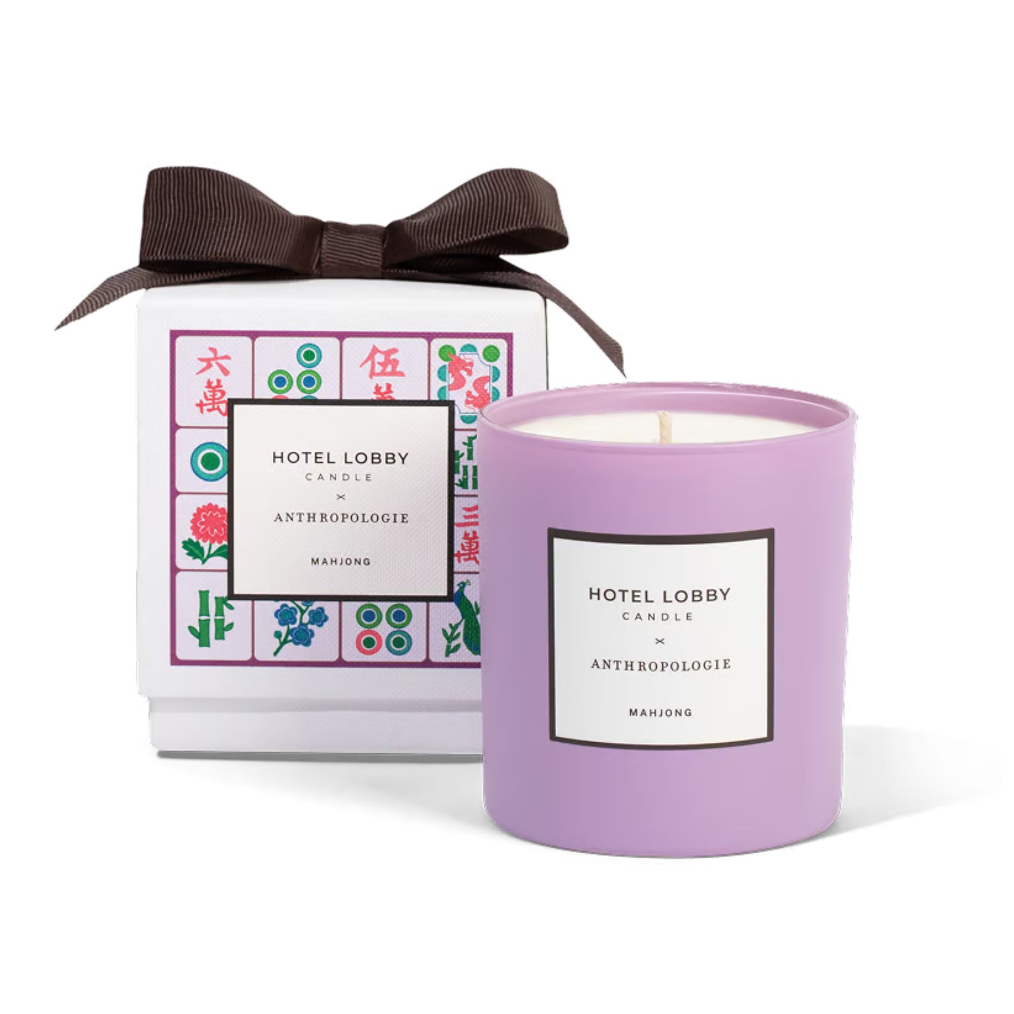 A purple candle next to a white gift box patterned with colored Mahjong tiles with a large brown ribbon on top